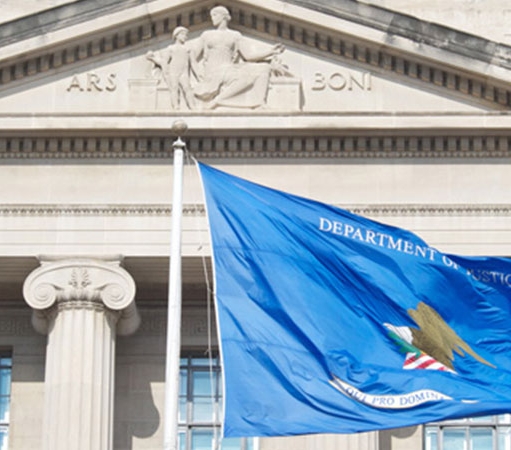 Blue DOJ flag in front of a DOJ building